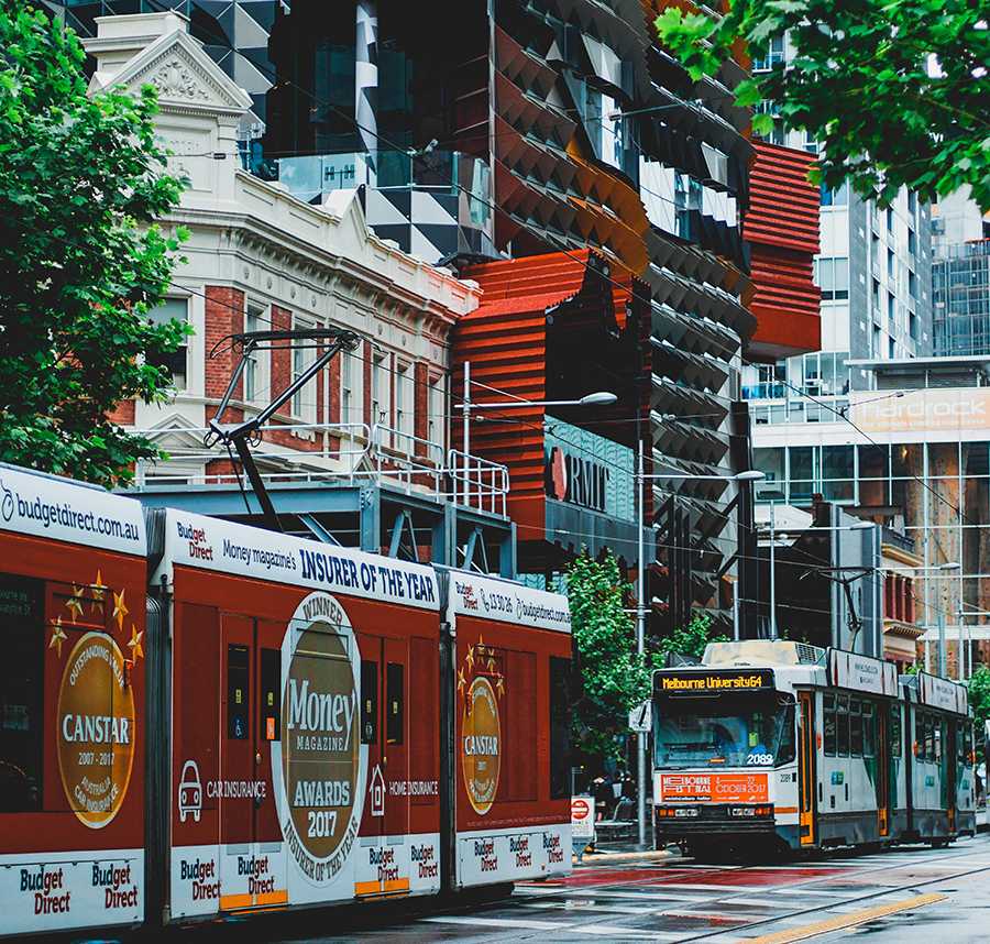 Two trams drive past RMIT on Swanston Street in Melbourne.